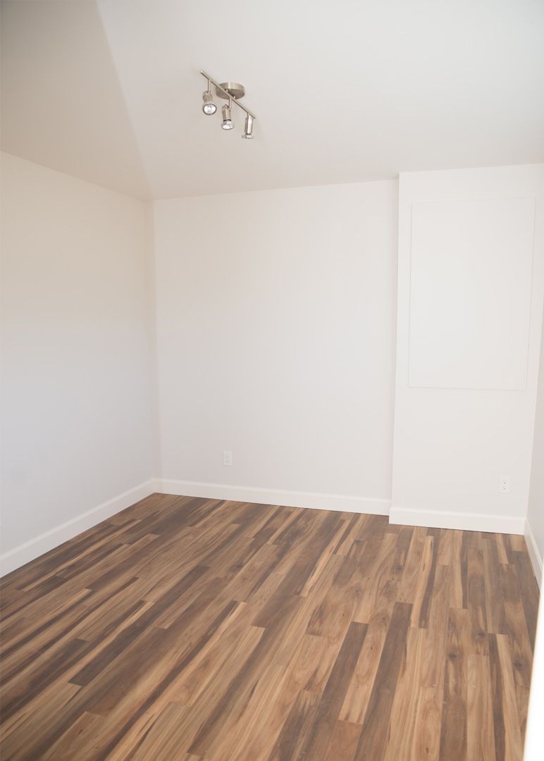 Une pièce vide avec du parquet et des murs blancs.