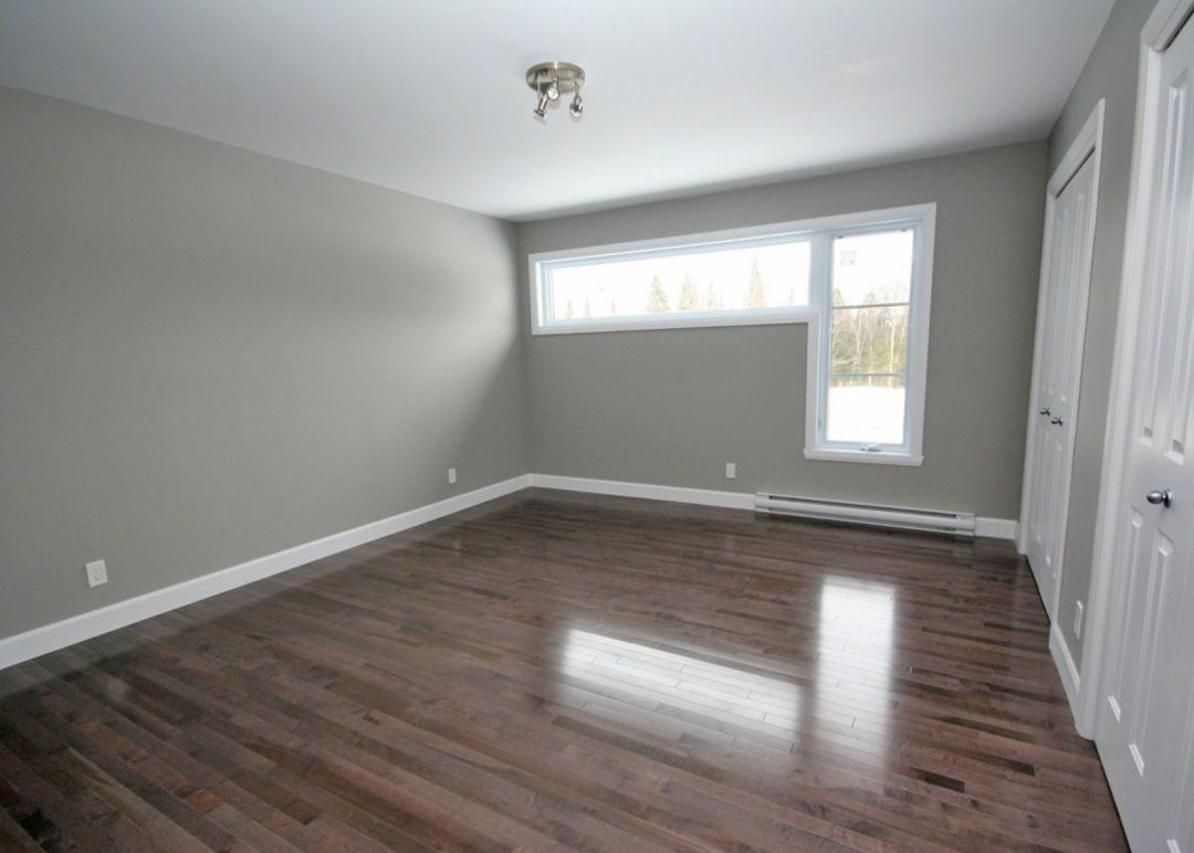 Une pièce vide avec du parquet et des murs gris