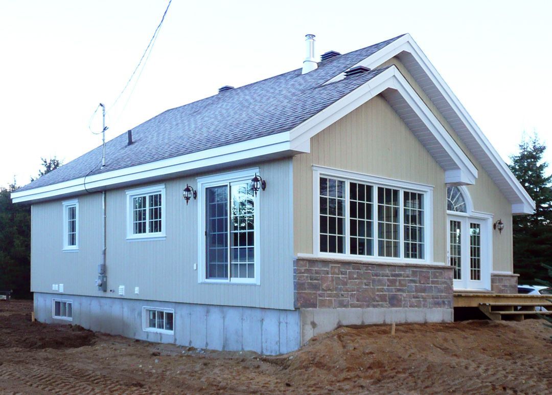 Une petite maison avec un toit gris et beaucoup de fenêtres
