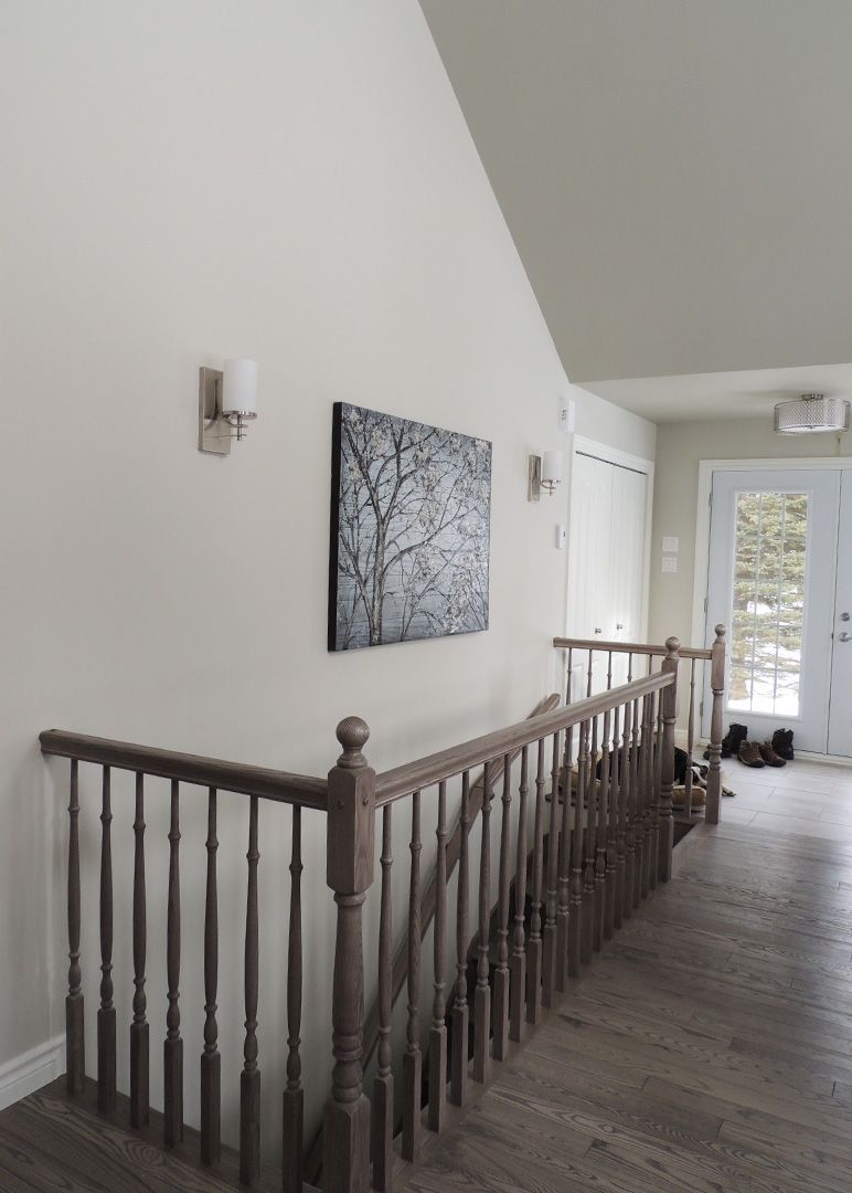 Un couloir avec des escaliers et un tableau sur le mur.