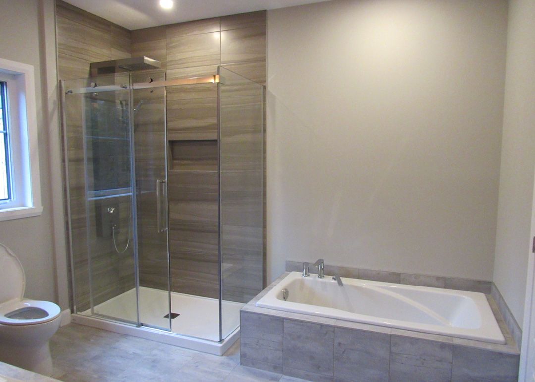 Une salle de bain avec baignoire, douche, WC et fenêtre.