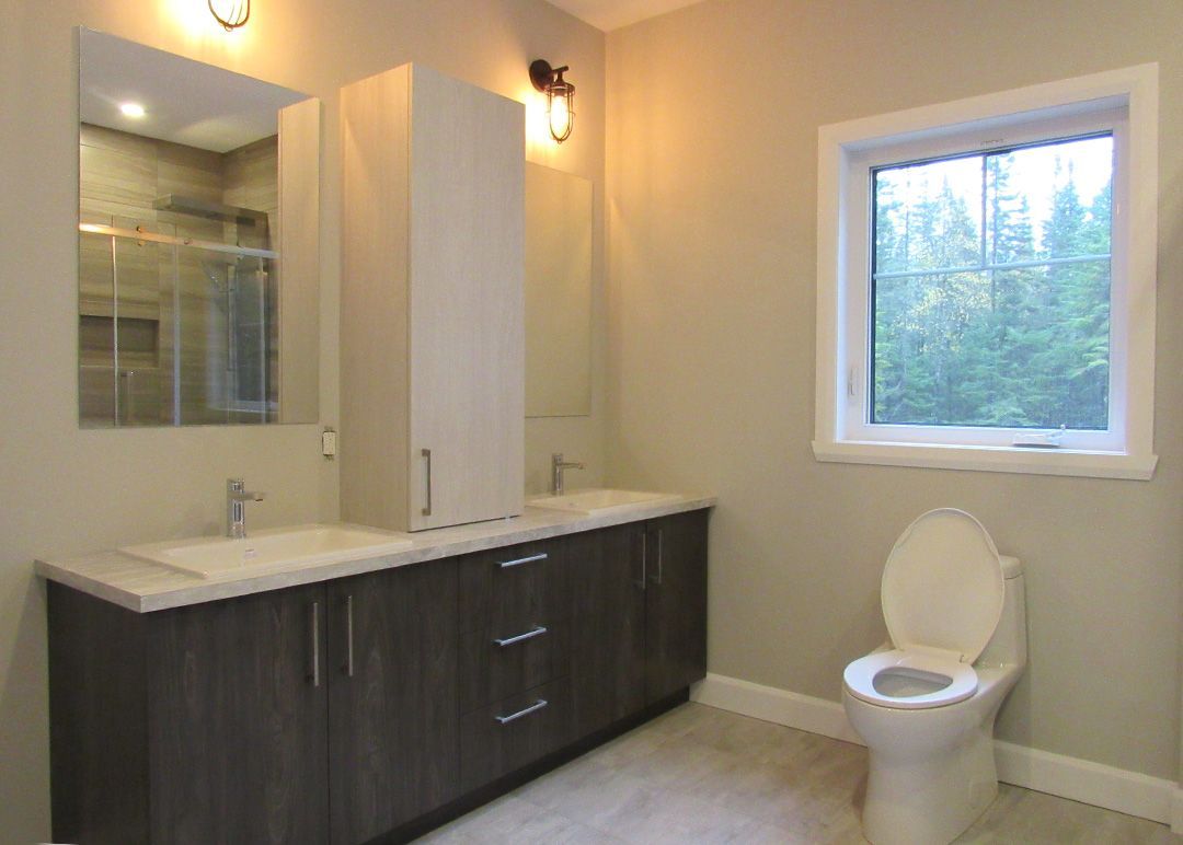 Une salle de bain avec WC, lavabo, miroir et fenêtre.
