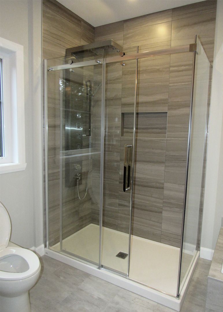 Une salle de bain avec WC et une cabine de douche avec portes coulissantes en verre.