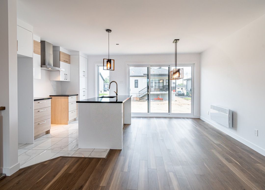 Une cuisine et un salon dans une maison vide avec du parquet.