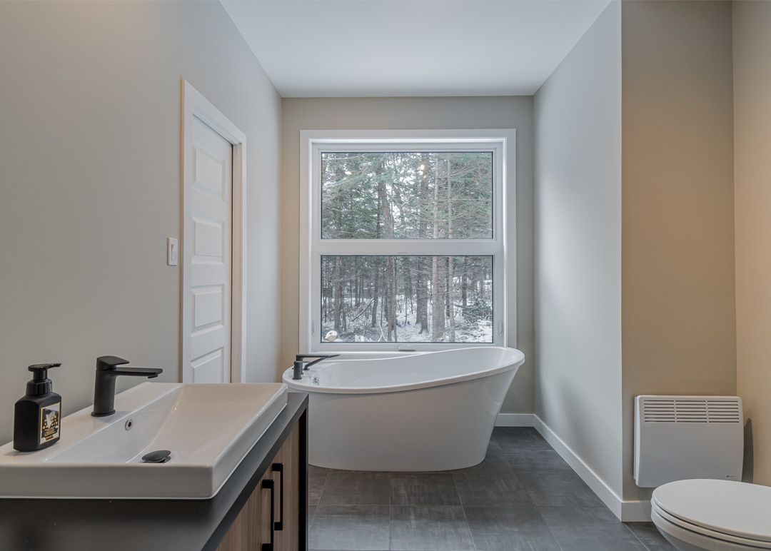 Une salle de bain avec baignoire, lavabo, toilettes et fenêtre.