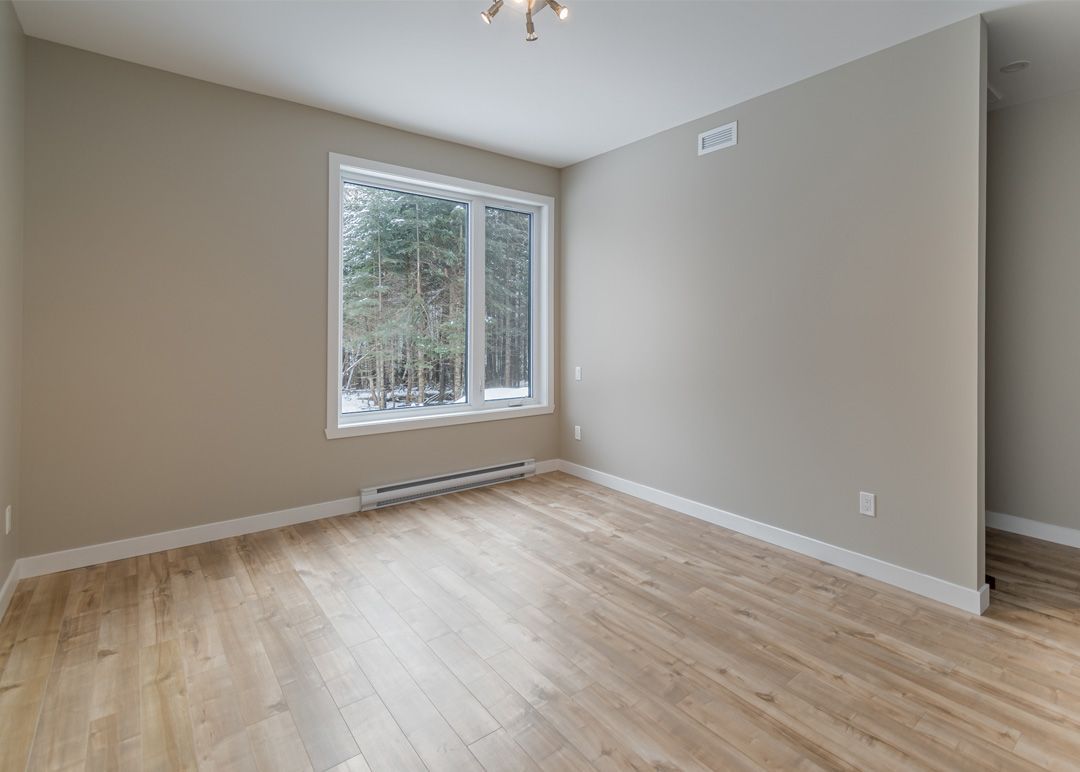 Une pièce vide avec du parquet et une grande fenêtre.