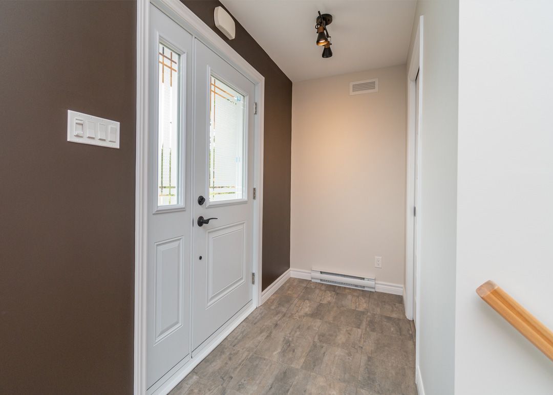 Un couloir avec une porte blanche et des murs marron