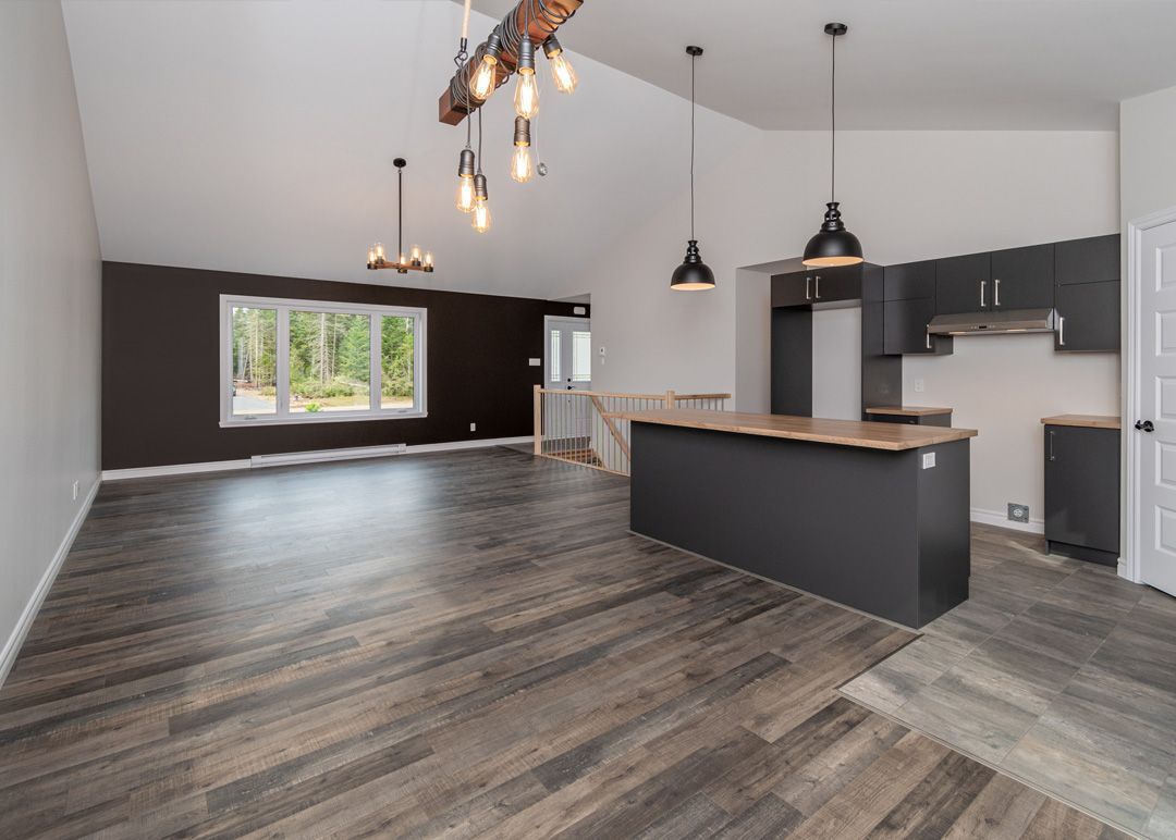Une grande pièce vide avec parquet et une cuisine.