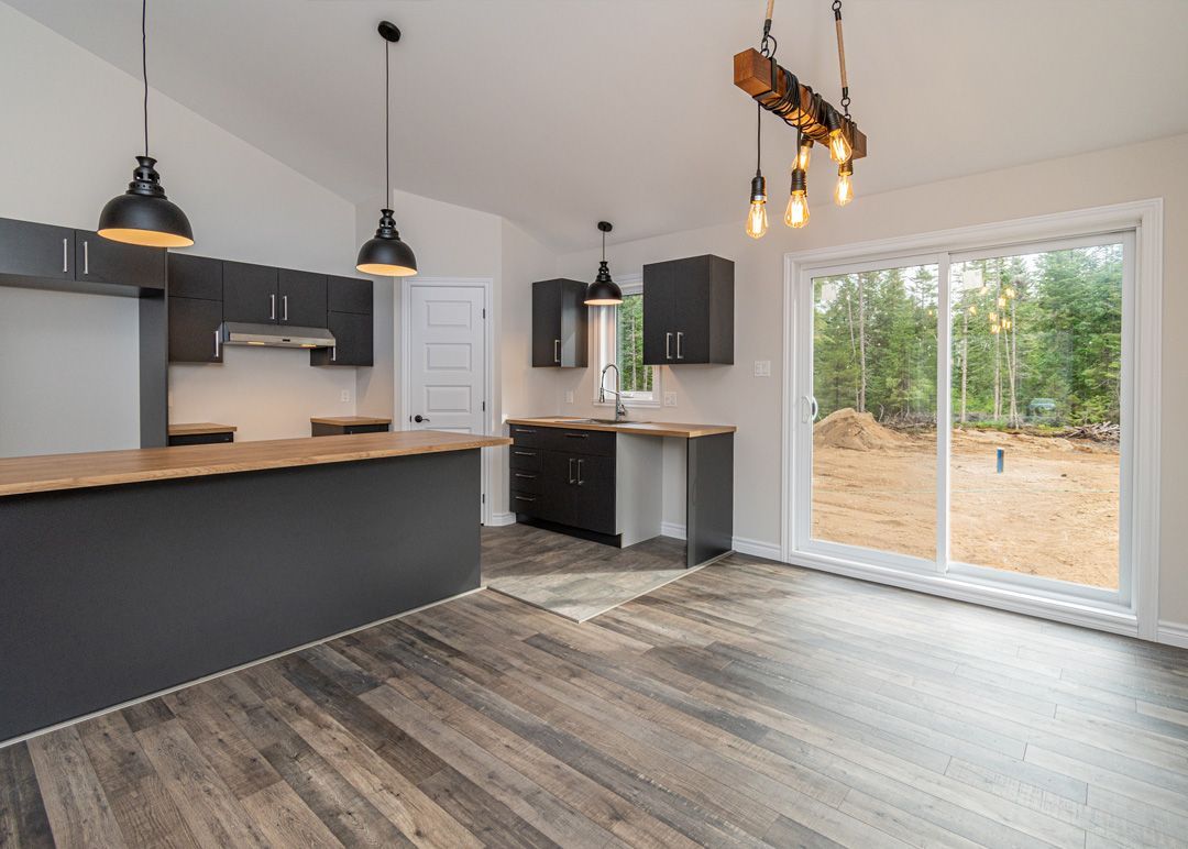 Une cuisine vide avec une porte coulissante en verre et un plancher en bois.