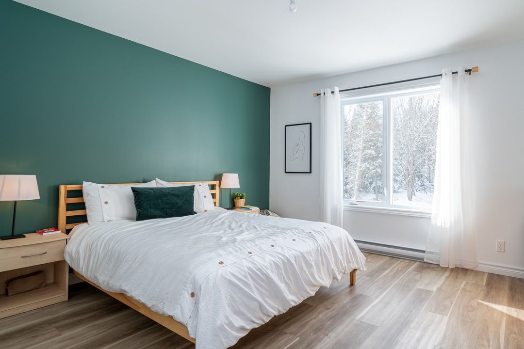Une chambre avec un lit, des tables de nuit, des lampes et un mur végétal.