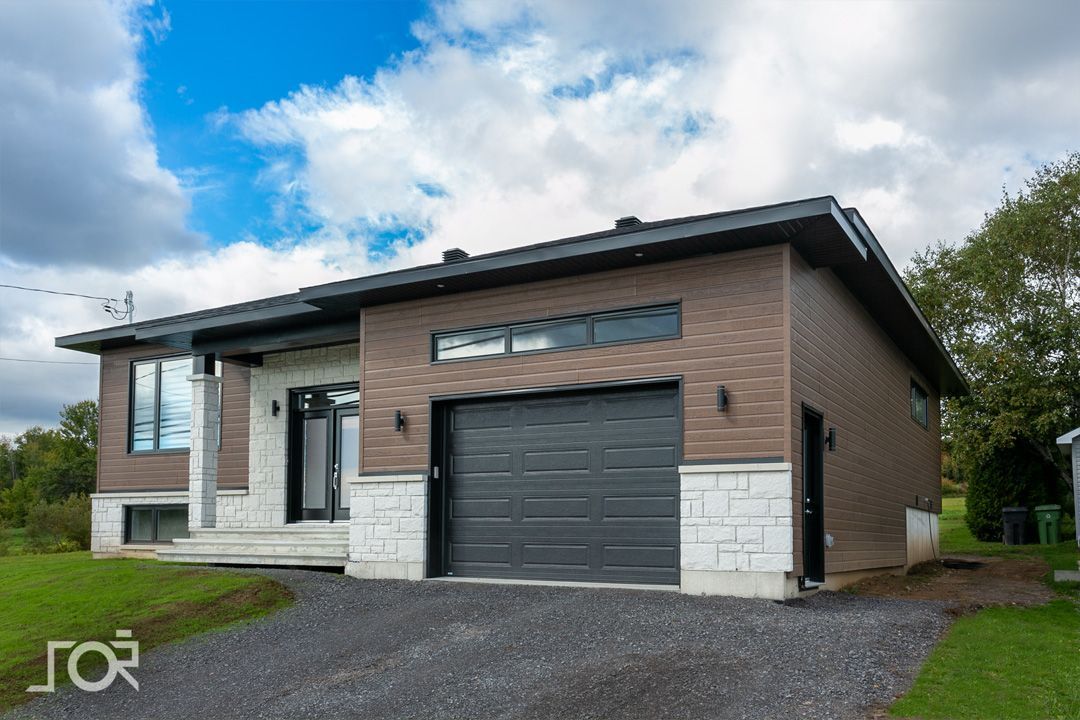 Une maison avec un garage et une allée devant.