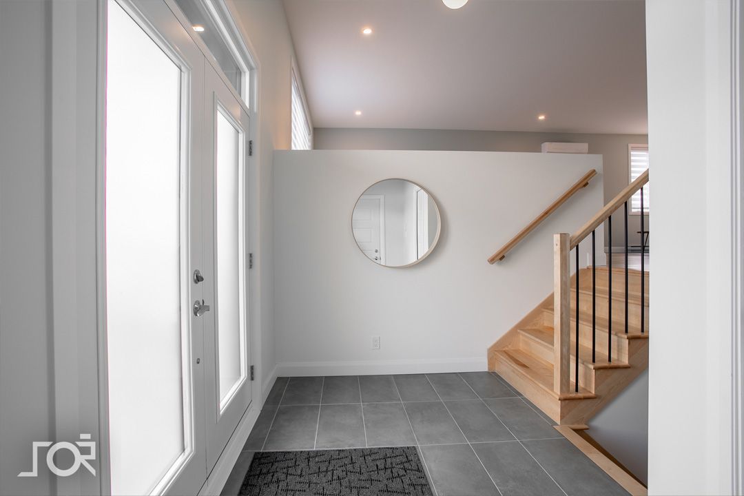 Un couloir avec des escaliers et un miroir sur le mur.