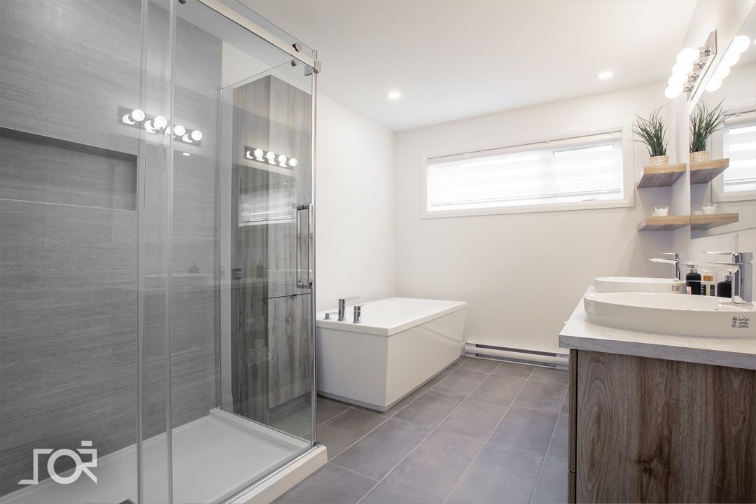 Une salle de bain avec deux lavabos, une baignoire et une douche à l'italienne.