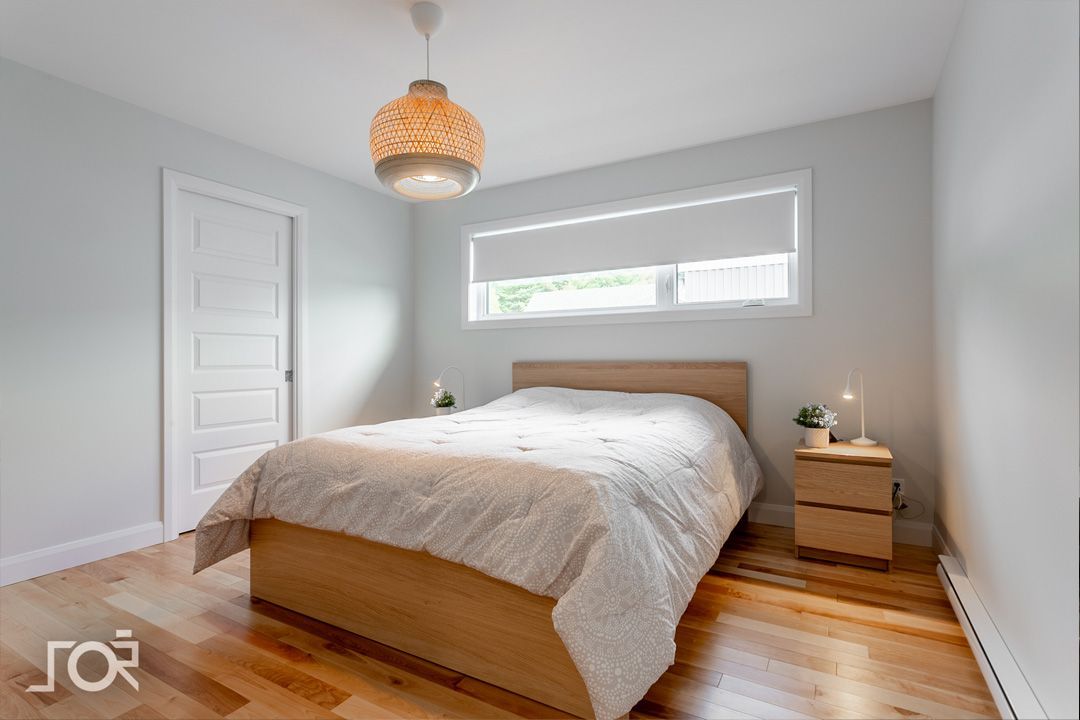 Une chambre avec un lit, une table de nuit et une fenêtre.