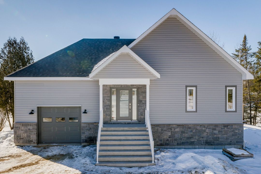 Une maison avec un garage et des escaliers dans la neige.
