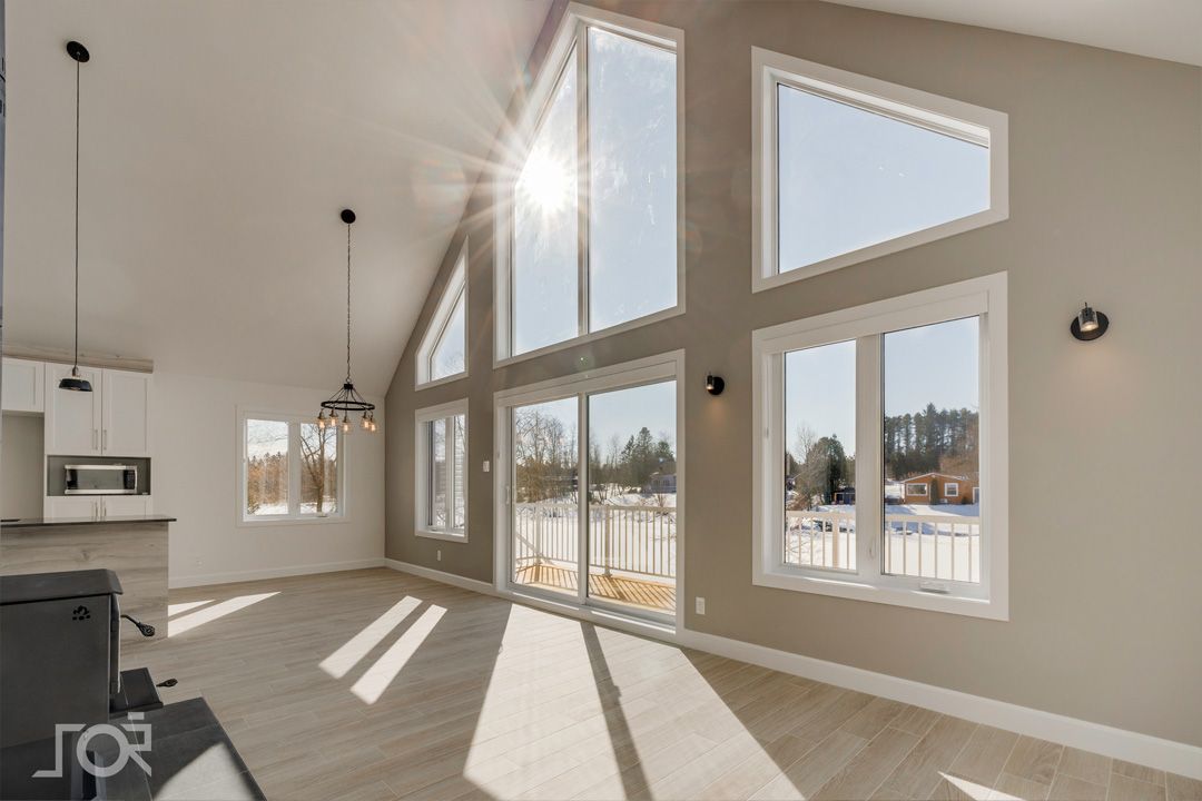Un salon avec beaucoup de fenêtres et le soleil qui brille à travers elles