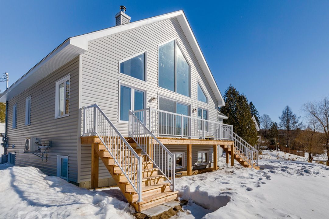 Une grande maison blanche avec une grande terrasse et des escaliers dans la neige.