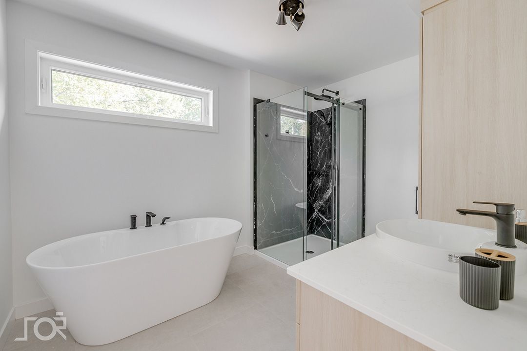 Une salle de bain avec baignoire, lavabo, douche et fenêtre.