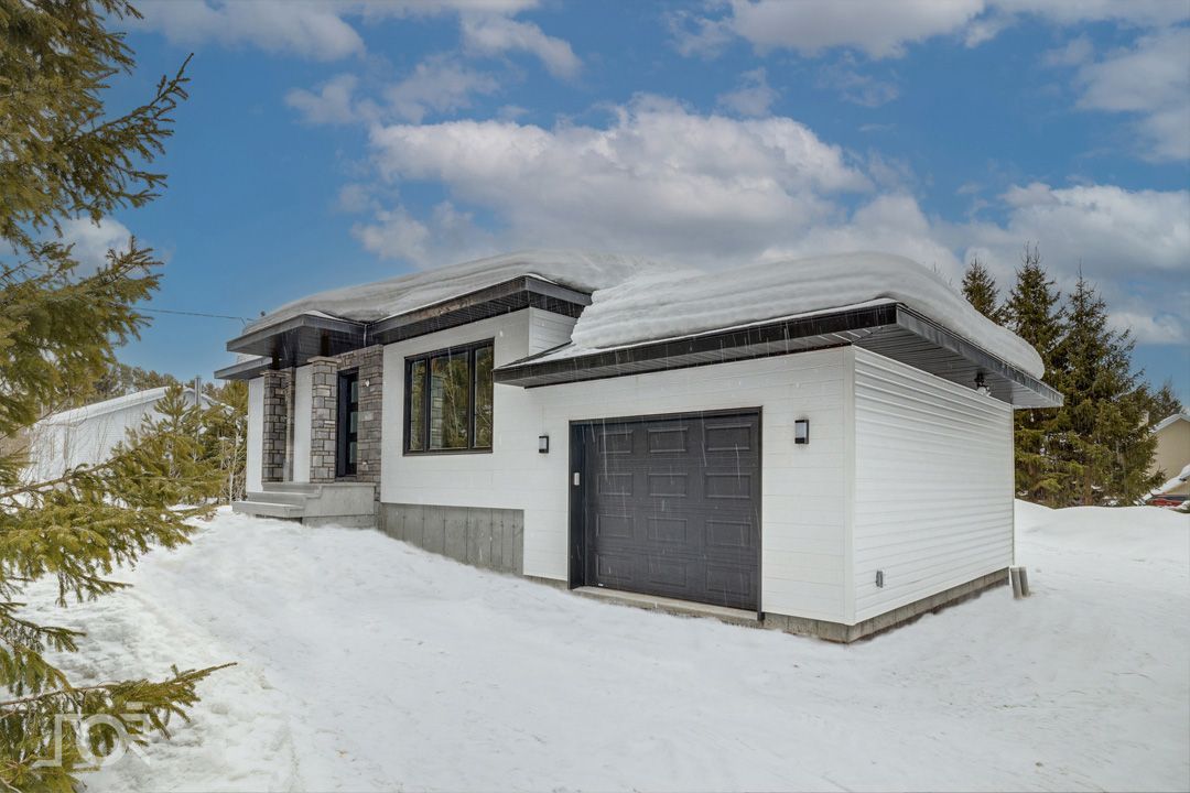 Une maison blanche avec un garage sous la neige.