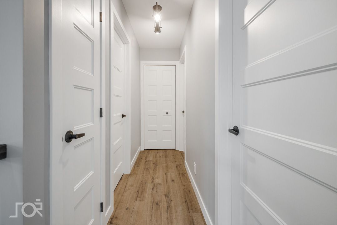 Un couloir avec des portes blanches et du parquet dans une maison.