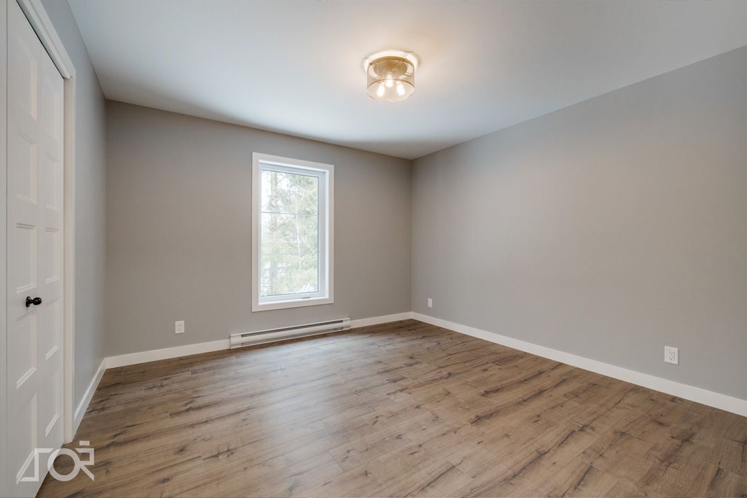 Une pièce vide avec du parquet et une fenêtre.