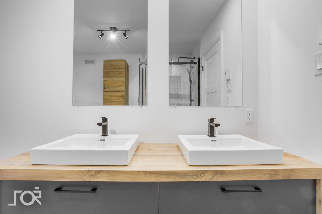 Une salle de bain avec deux lavabos et deux miroirs.