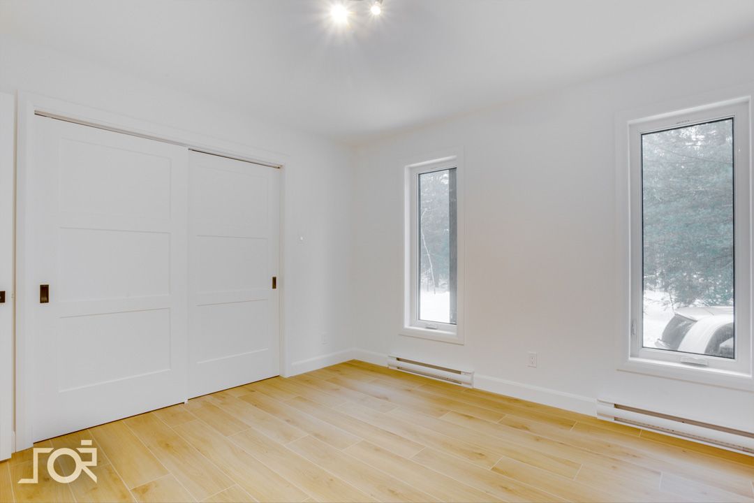 Une pièce vide avec du parquet et deux fenêtres.