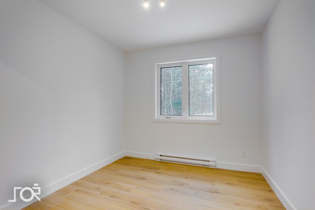 Une pièce vide avec du parquet et une fenêtre