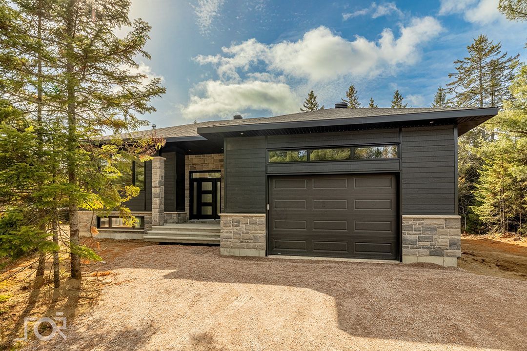 Une maison moderne avec garage au milieu d'une forêt.