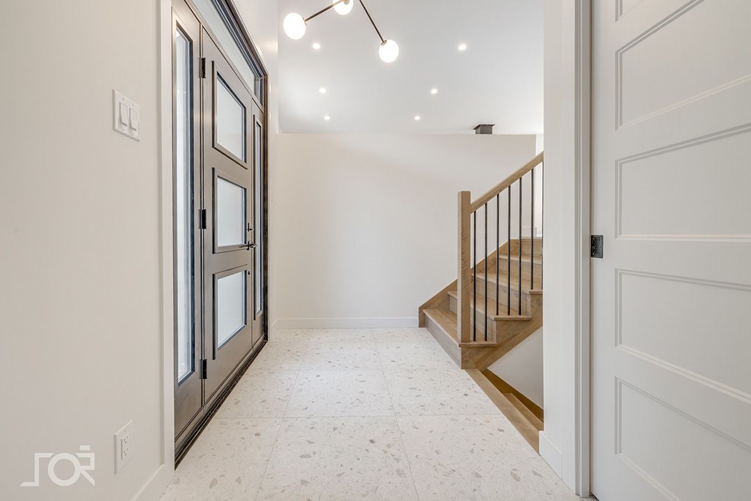 Un couloir avec une porte et des escaliers dans une maison