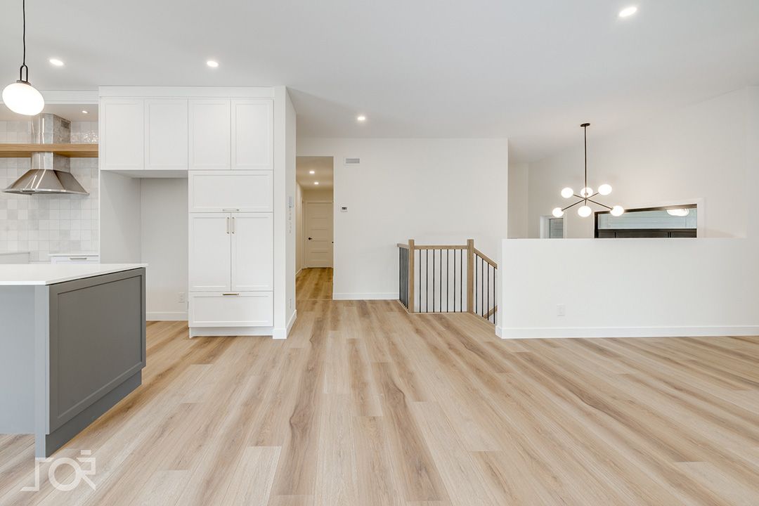 Une cuisine vide avec du parquet et des armoires blanches