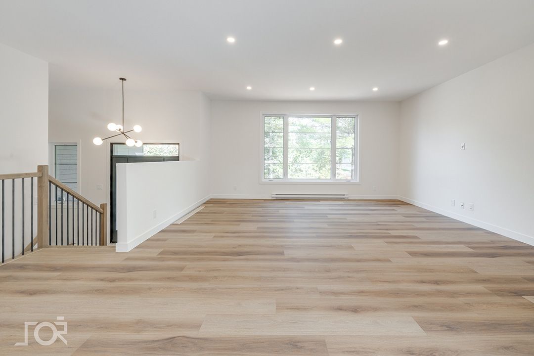 Un salon vide avec du parquet et un escalier.