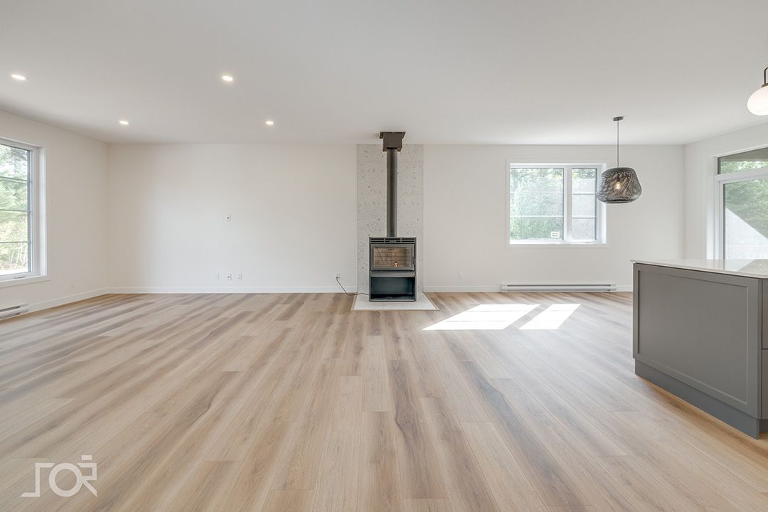 Un salon vide avec du parquet et une cheminée
