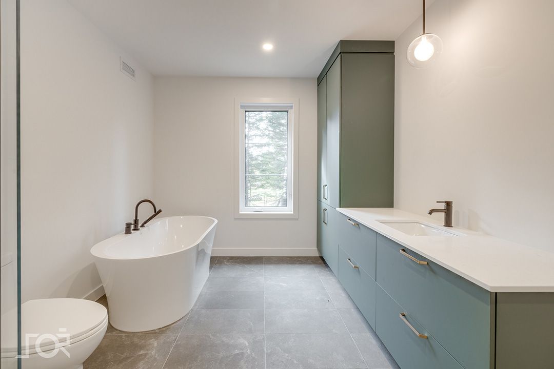 Une salle de bain avec baignoire, lavabo, toilettes et fenêtre.