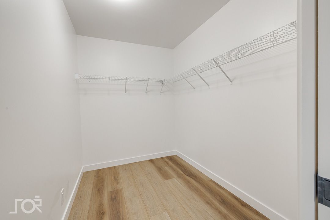 Un dressing vide avec du parquet et des murs blancs.