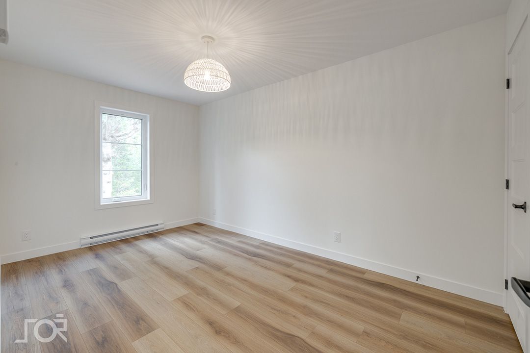 Une pièce vide avec du parquet et des murs blancs.