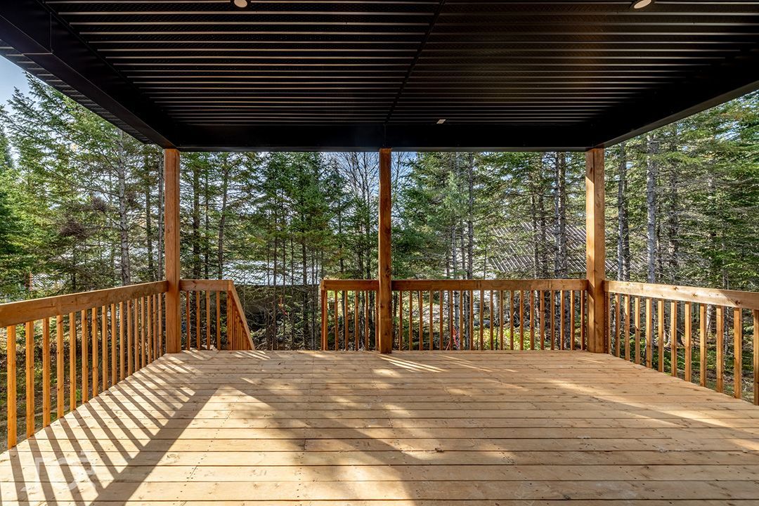 Une terrasse en bois vide avec vue sur une forêt.