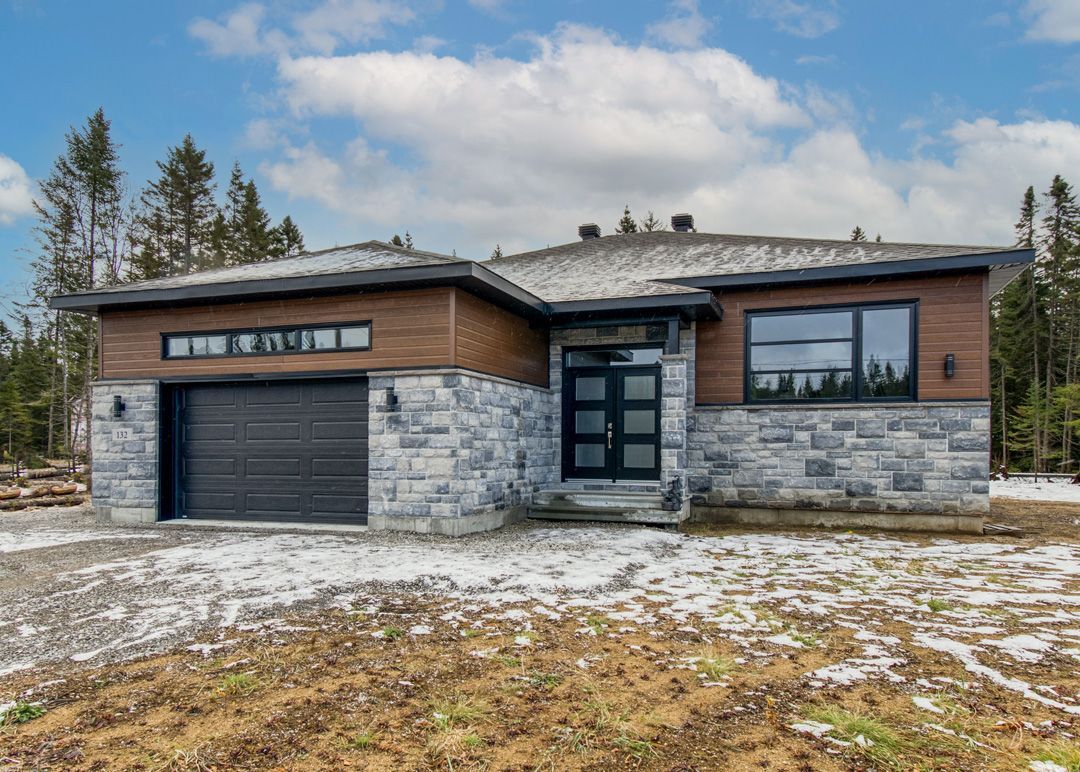 La façade d'une maison avec un garage et beaucoup de neige au sol.