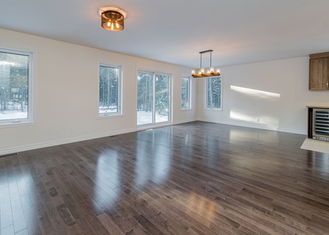 Un salon vide avec du parquet et beaucoup de fenêtres.