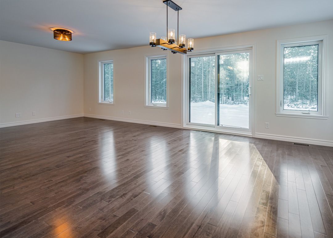 Un salon vide avec du parquet et un lustre.