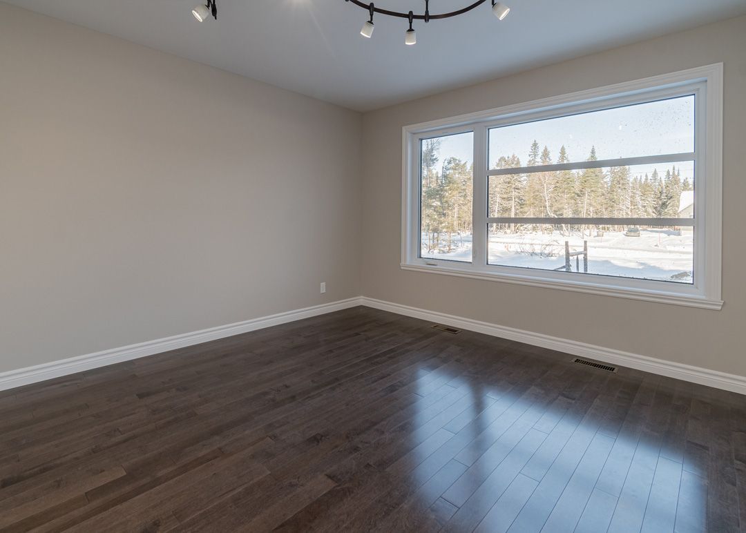 Une pièce vide avec du parquet et une grande fenêtre.