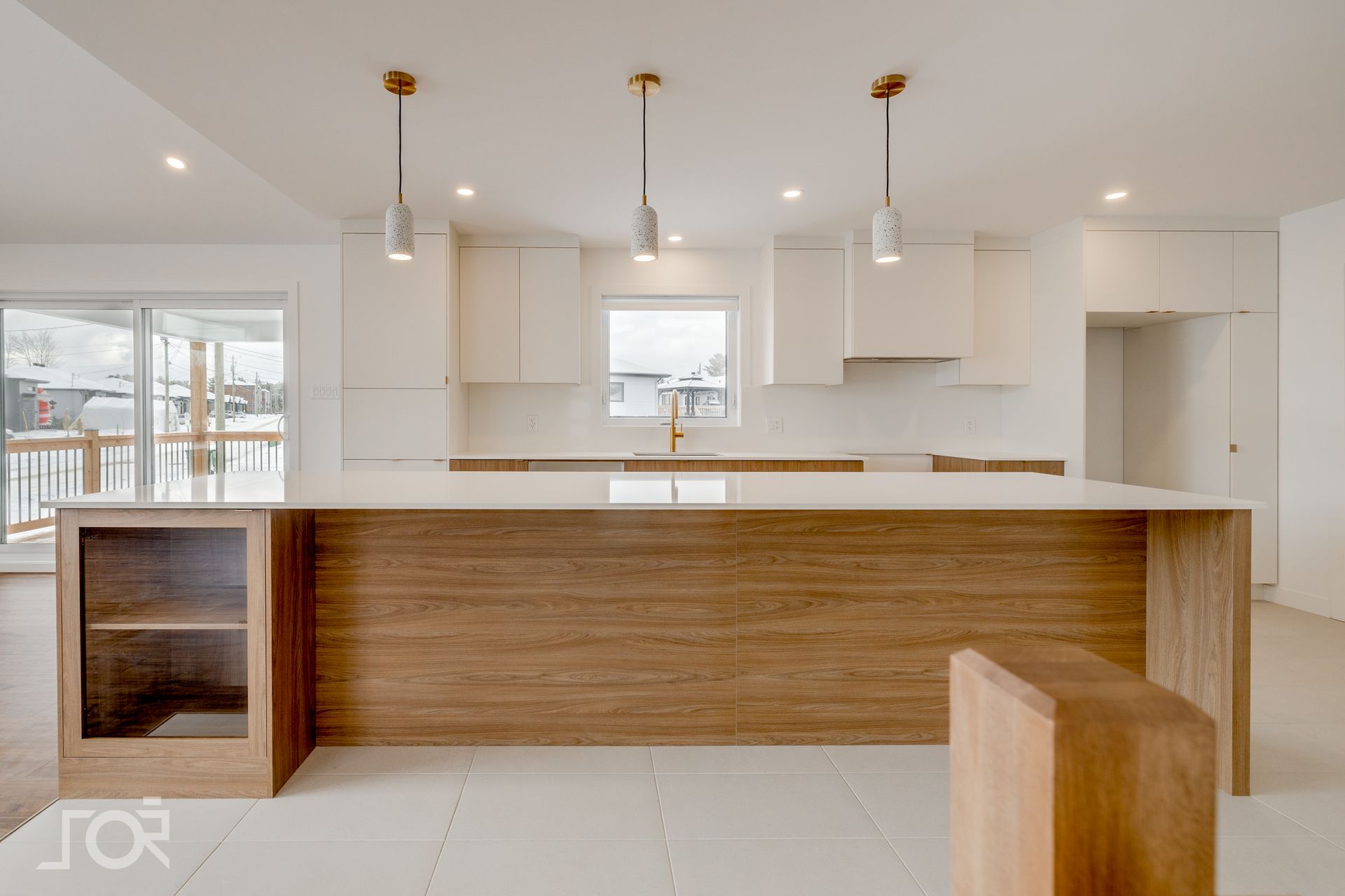 Cuisine moderne avec îlot en bois, placards blancs et suspensions lumineuses.