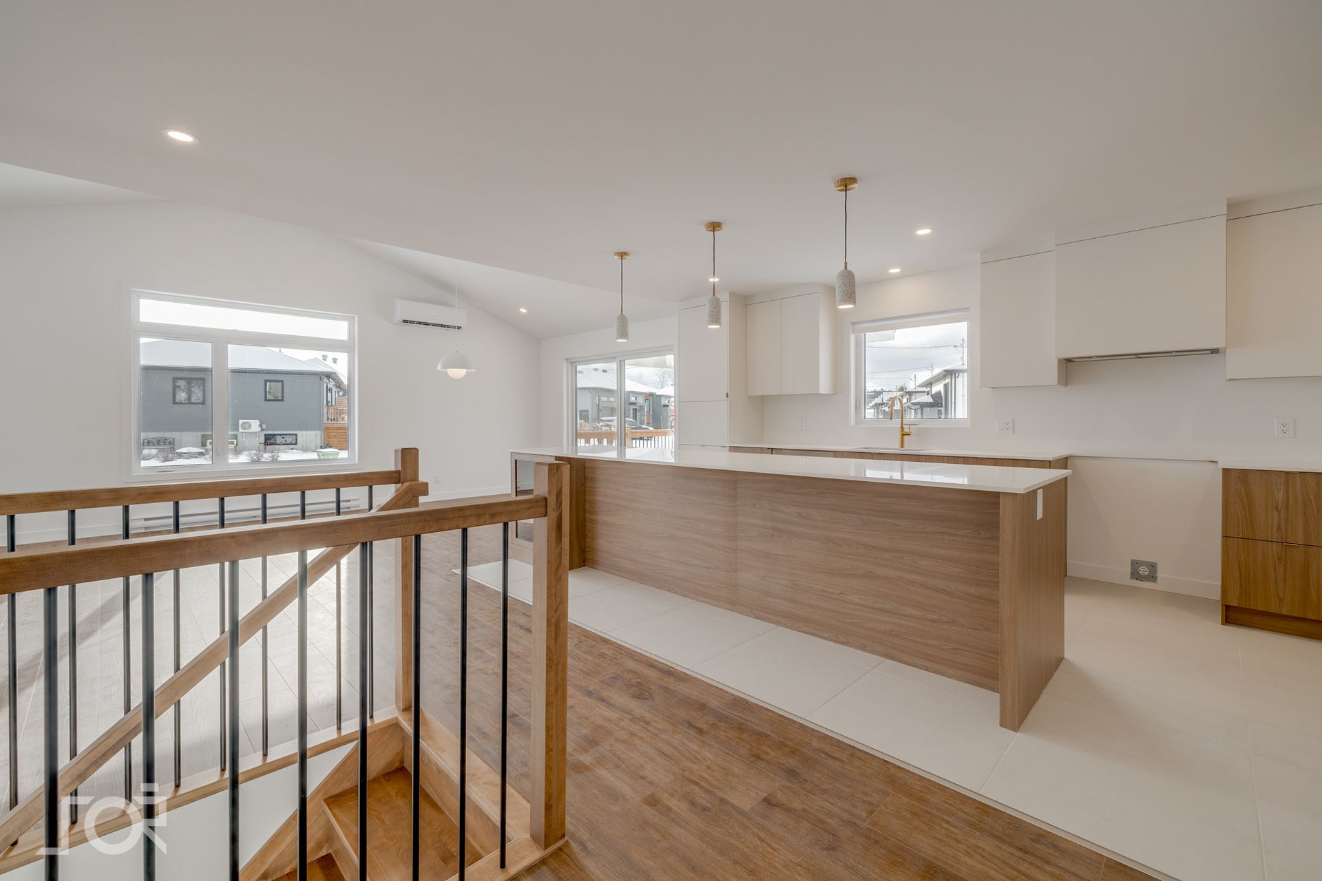 Cuisine moderne avec îlot en bois clair, placards blancs et escalier descendant.