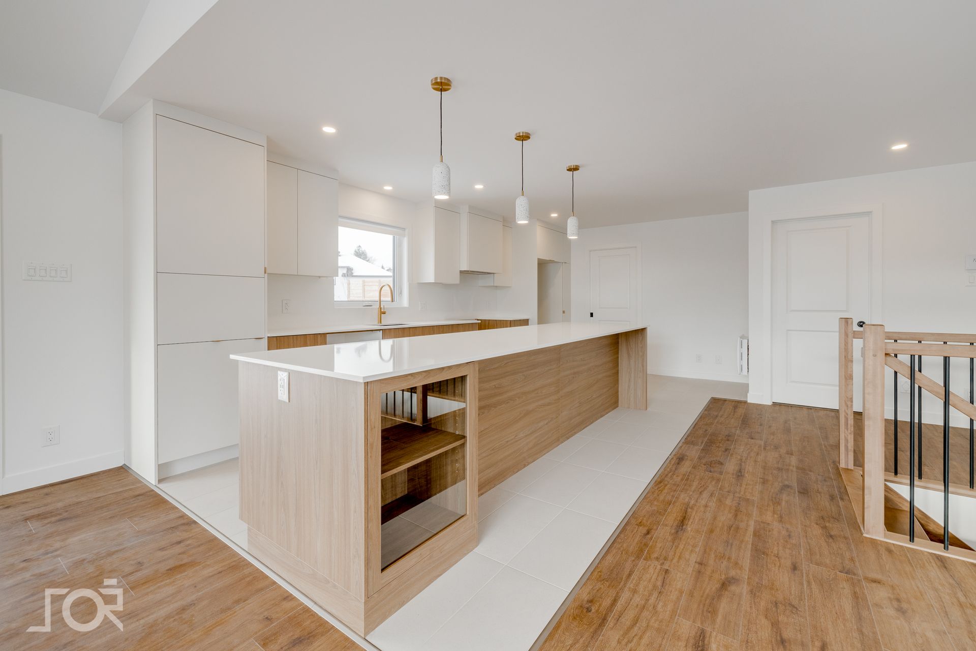 Cuisine moderne avec armoires blanches, îlot en bois clair, touches dorées et parquet.