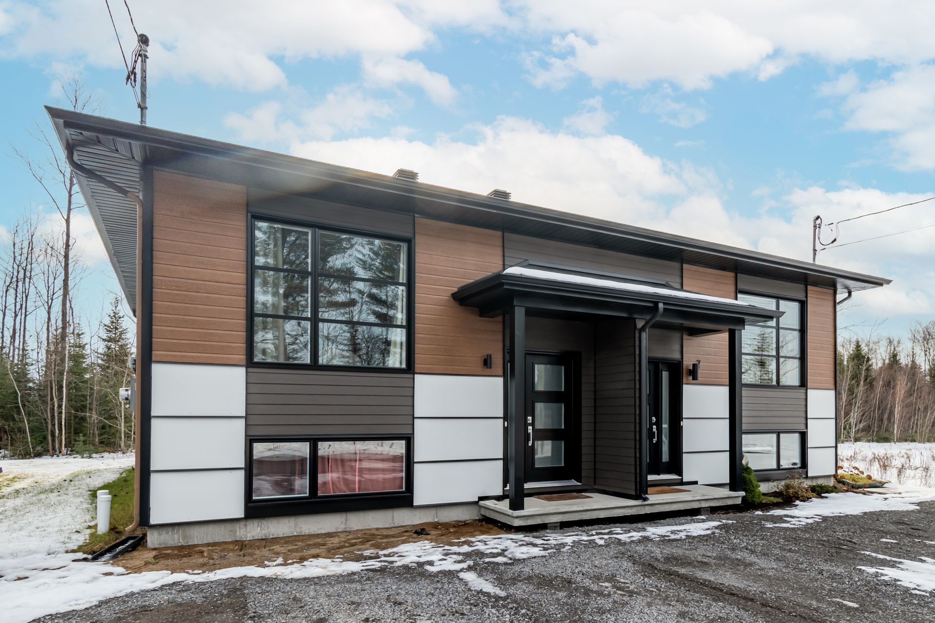 Une grande maison avec beaucoup de fenêtres se trouve au milieu d'un champ enneigé.
