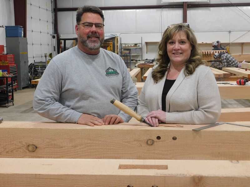 A man and a woman are standing next to a wooden beam.