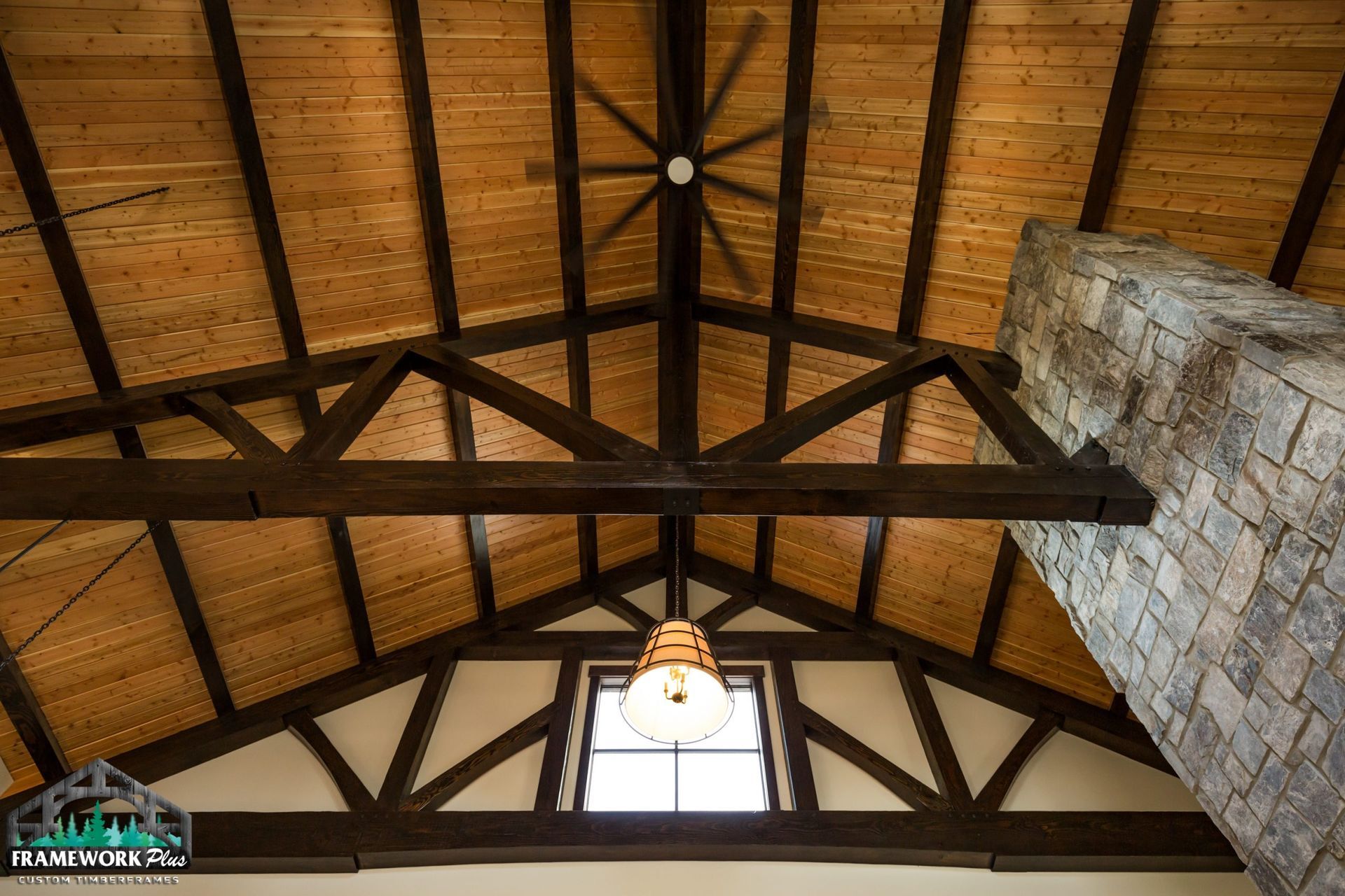A wooden ceiling with a ceiling fan and a window