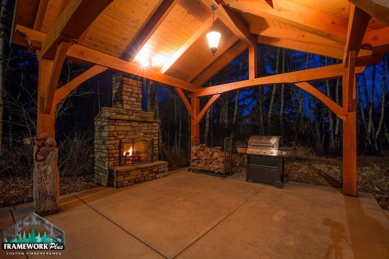 A wooden pavilion with a fireplace and a grill