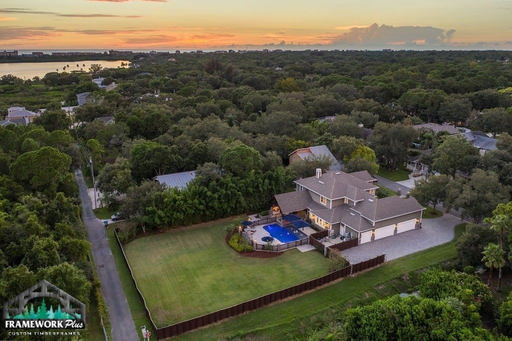 An aerial view of a large house surrounded by trees and a pool.