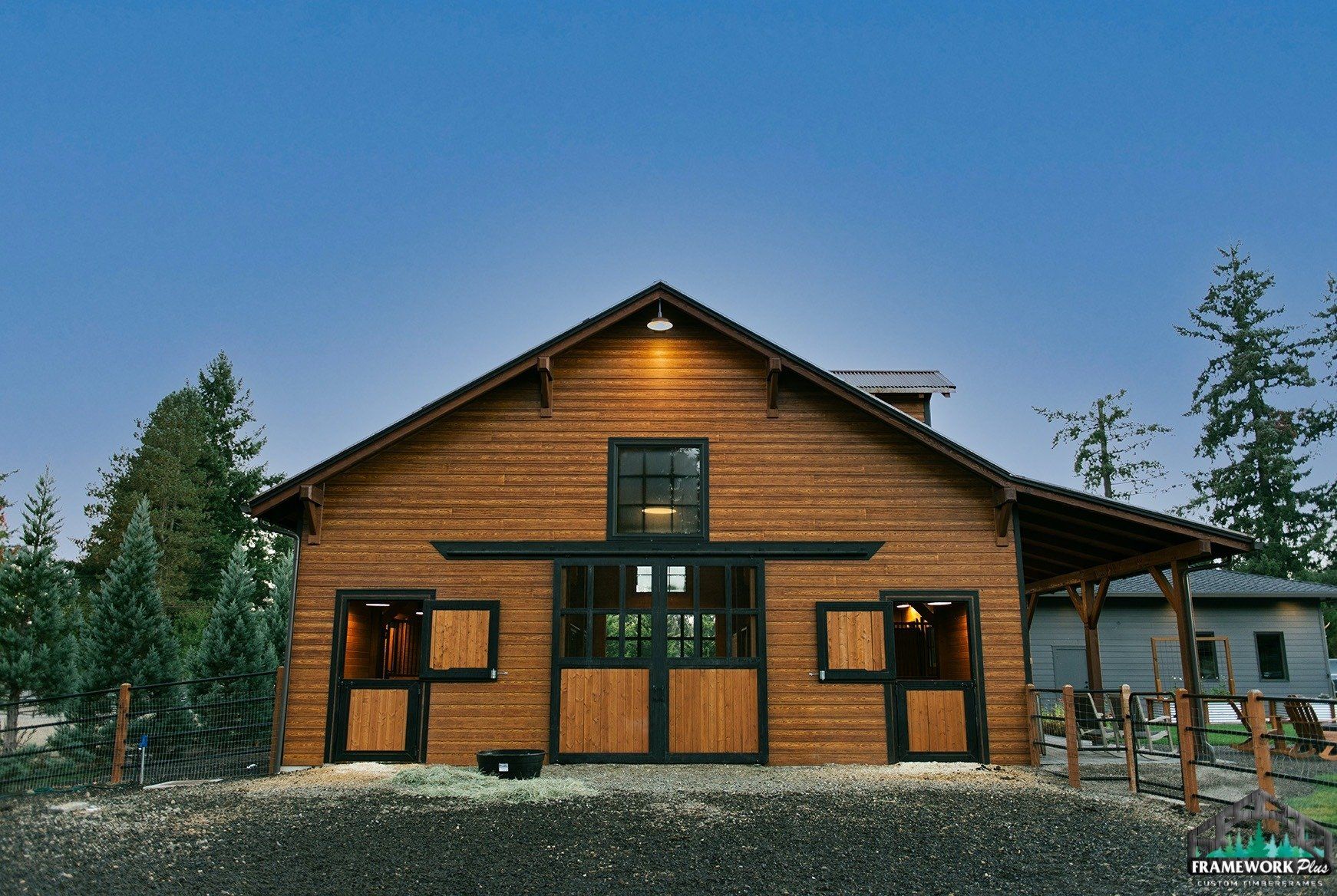 A large wooden barn with a fence around it and a blue sky in the background.